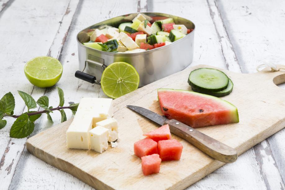 Lunch box, preparation of watermelon salad with feta, cucumber, ment and lime dressing